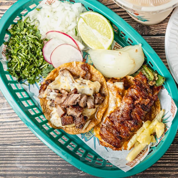 Two Taquitos Don Agaves tacos with meat and cheese, served with cilantro, onions, radishes, and lime.